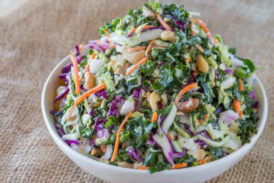 An easy filling delicious crunch and creamy Kale Salad with cashews and a lemon greek yogurt dressing.