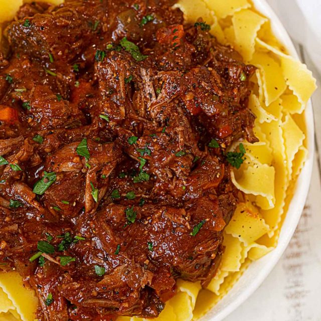 Healthier Beef Ragu over pappardelle pasta in white bowl
