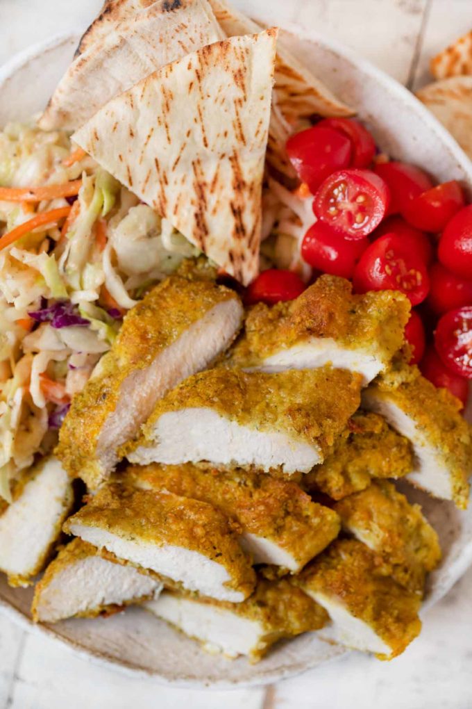 Falafel Crusted Chicken sliced in bowl with slaw and pita bread