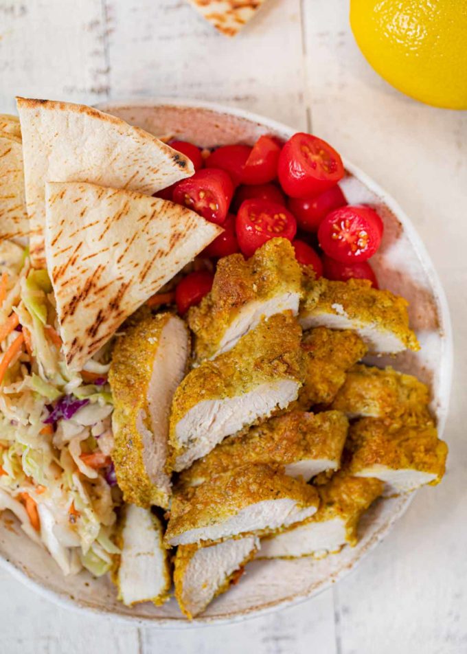 Falafel Crusted Chicken sliced in bowl with slaw and pita bread