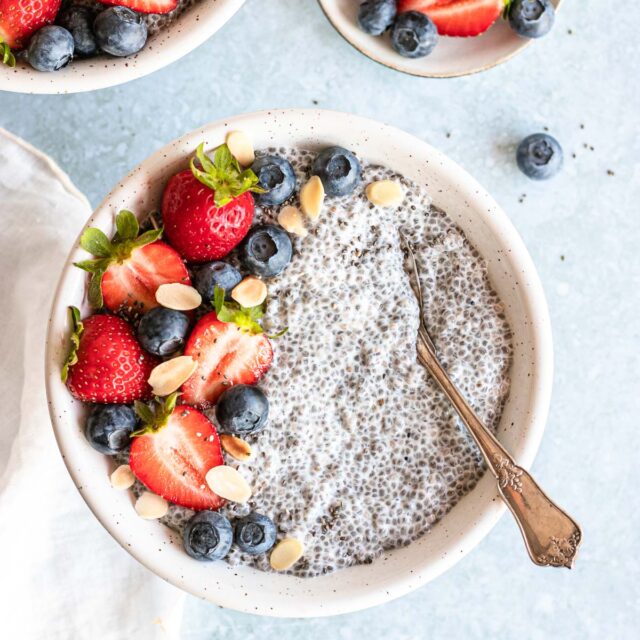 Vanilla Chai Pudding in bowl with berries on top and spoon in the bowl