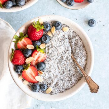 Vanilla Chai Pudding in bowl with berries on top and spoon in the bowl