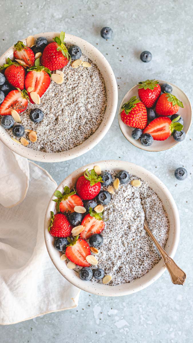 Two bowls of Vanilla Chai Pudding with berries in top and on the side