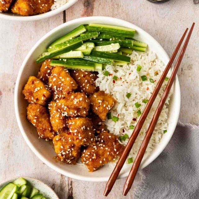 Baked Sesame Chicken in a bowl with chopsticks