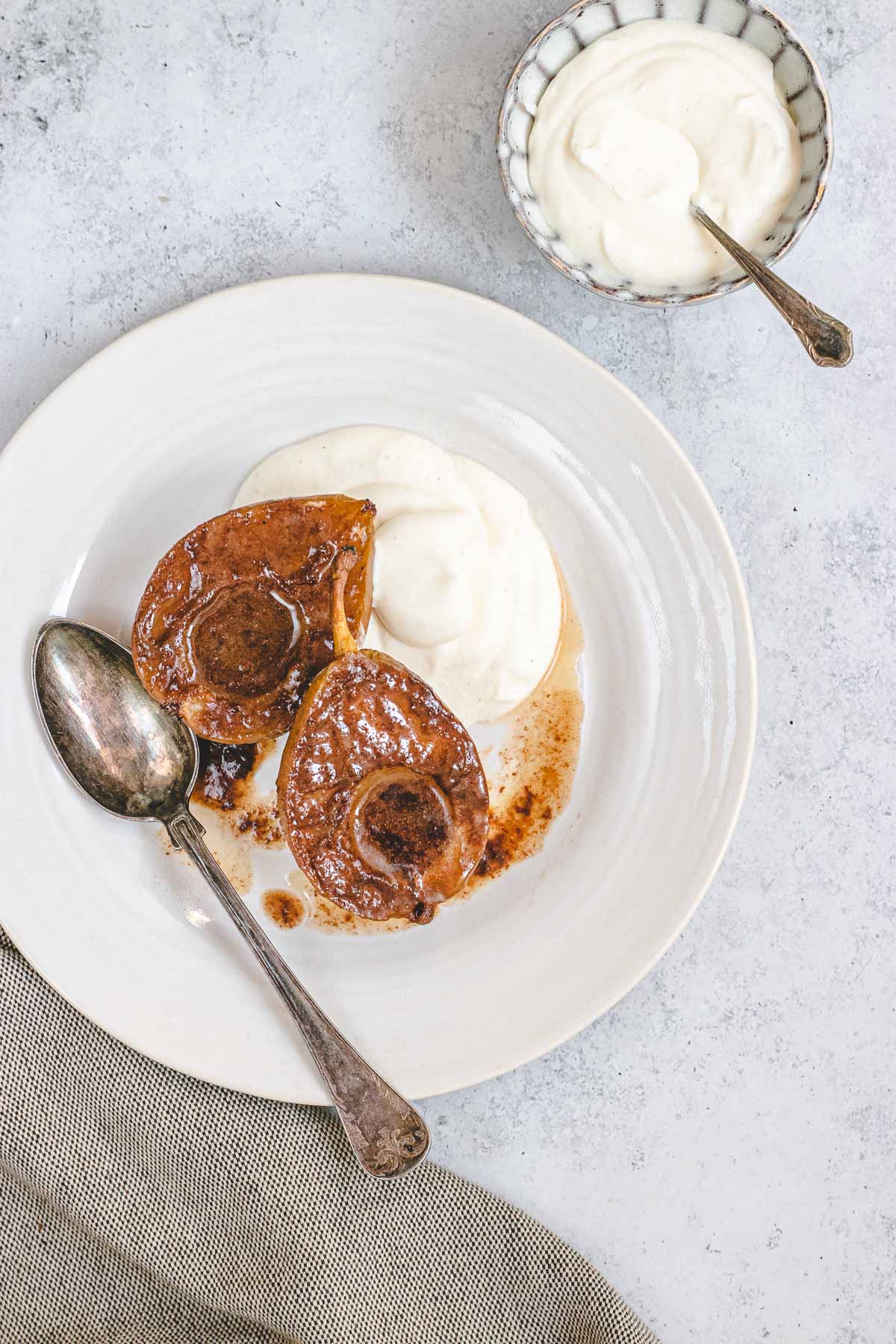 Baked Pears in a bowl with spoon and a side of cream