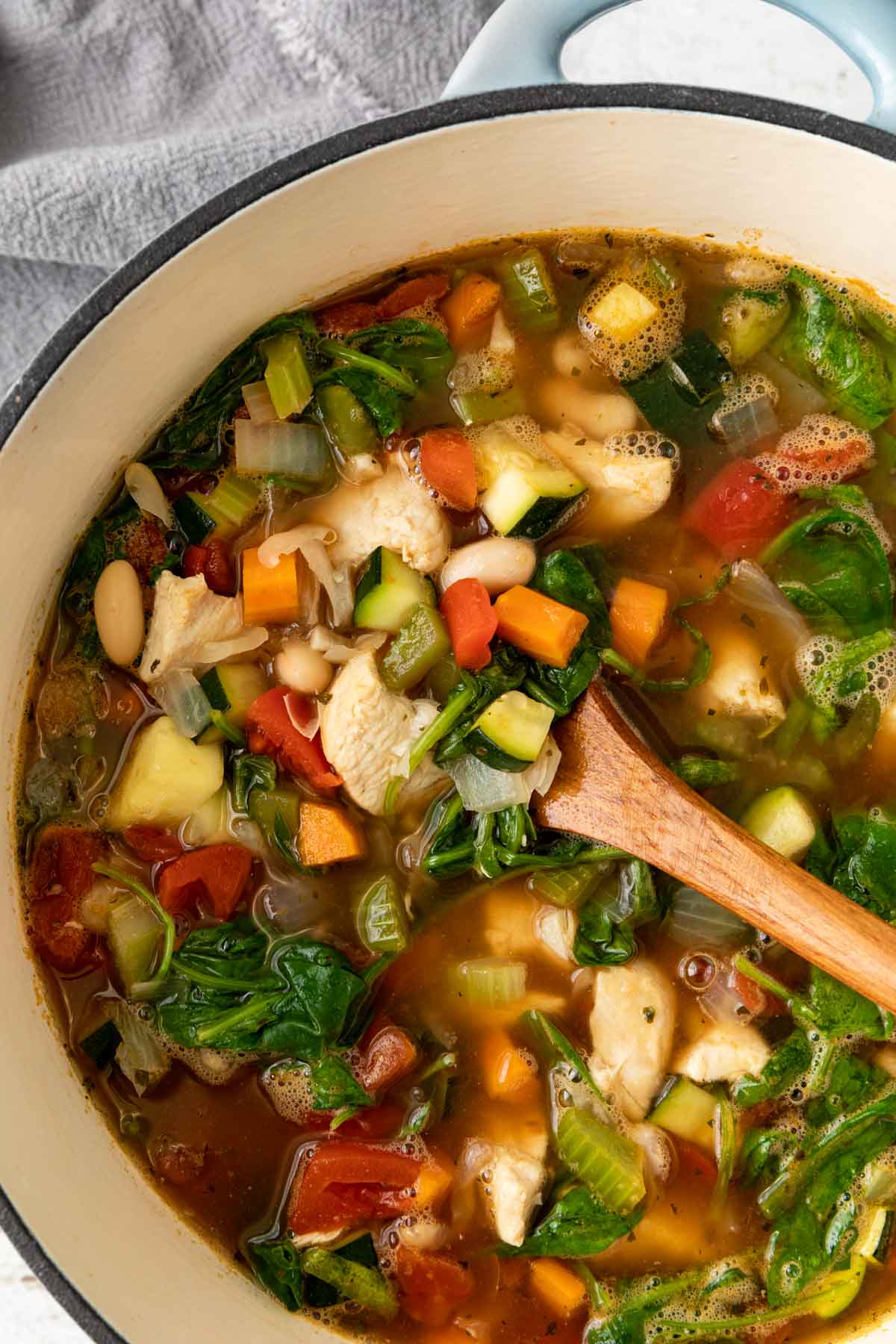 Tuscan Vegetable Soup in a pot with a wooden spoon