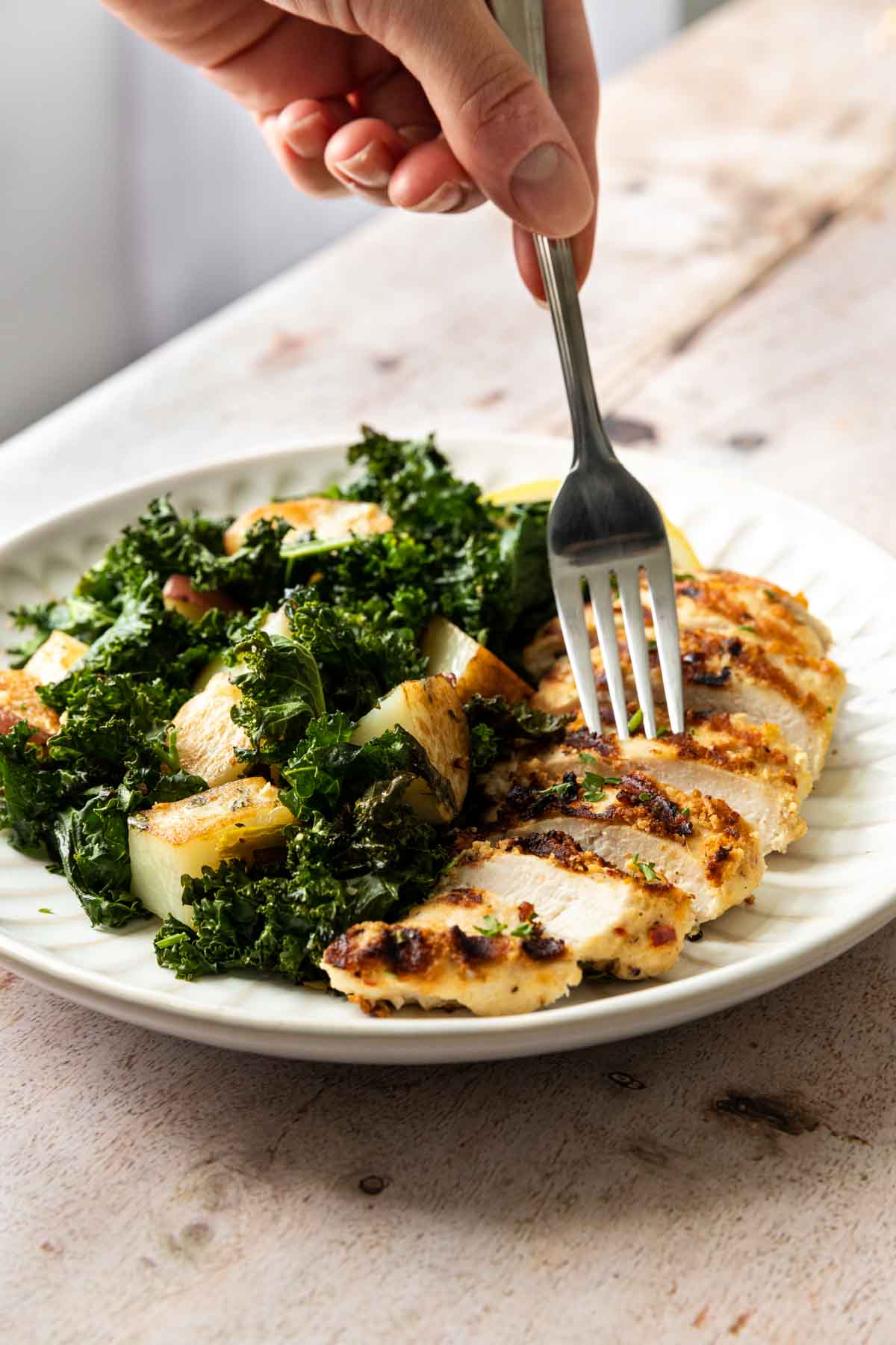 Sheet Pan Roasted Garlic Chicken with Kale and Potatoes on a plate with a fork