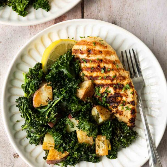 Sheet Pan Garlic Chicken with Kale and Potatoes on a plate with a fork