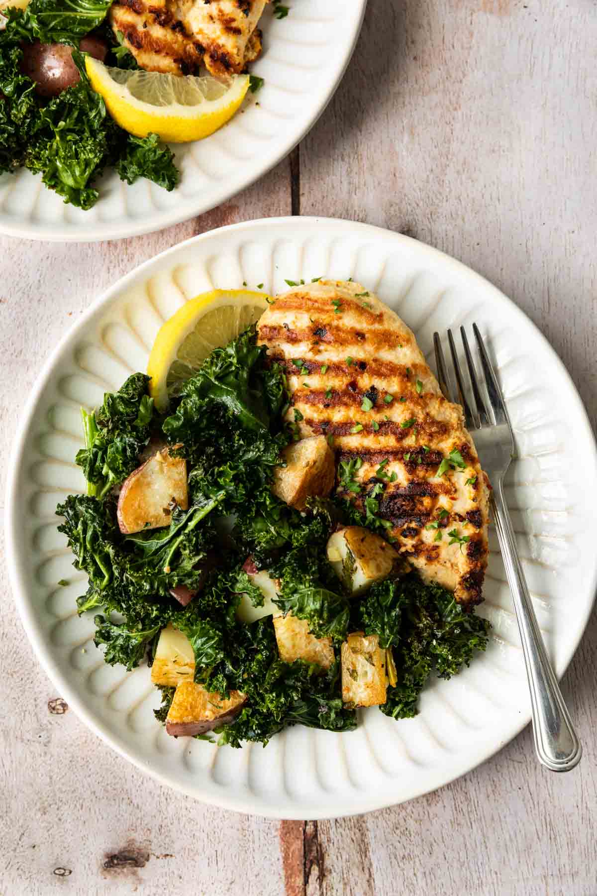 Sheet Pan Garlic Chicken with Kale and Potatoes on a plate with a fork