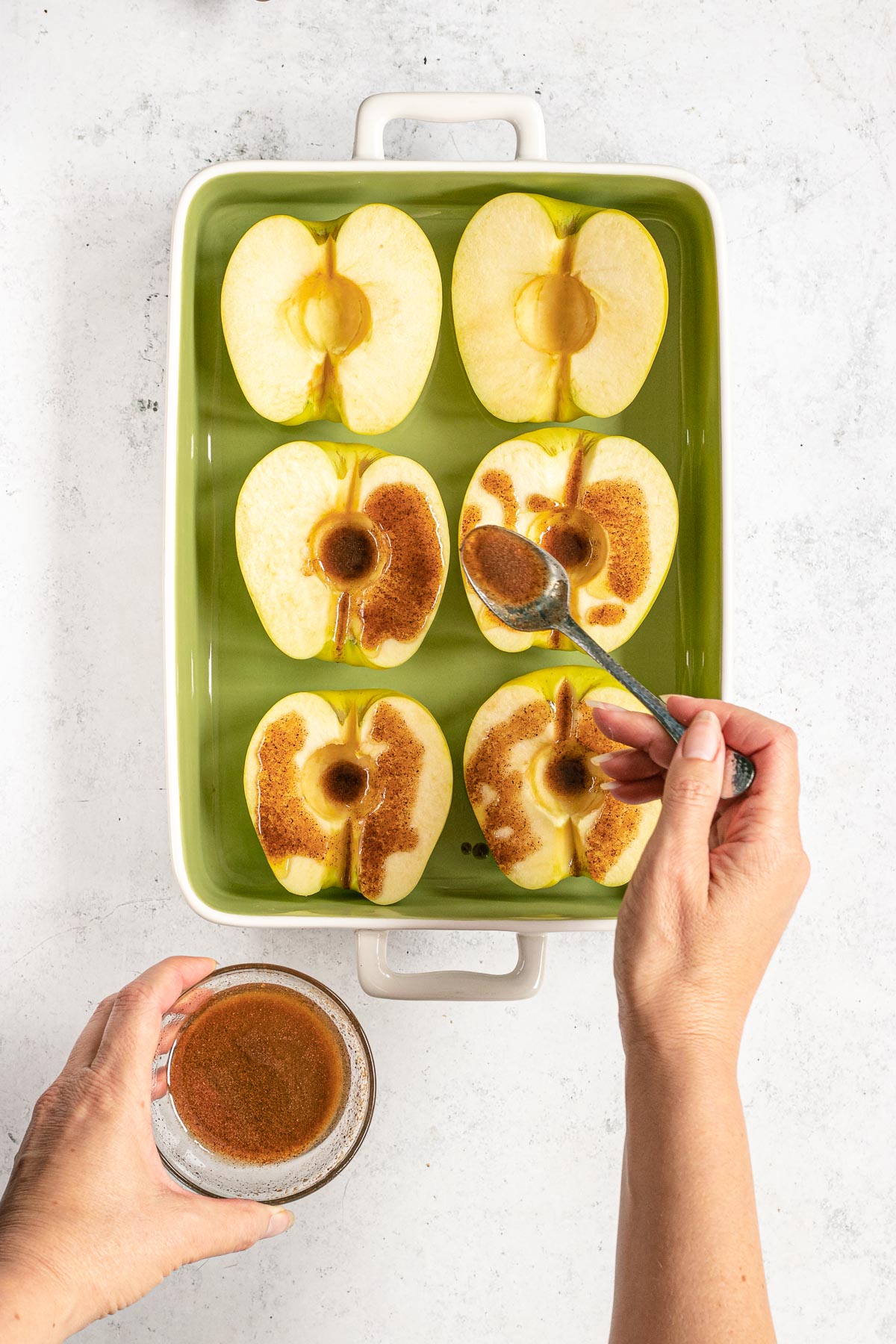 Healthy Cinnamon Baked Apples halved apples in baking dish topped with cinnamon butter